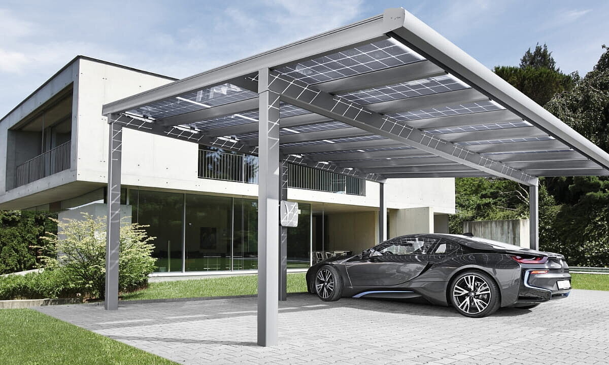 Ein Auto steht unter einem Solarcarport vor einem großen Haus